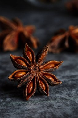 Arka planda koyu mavi tonlarda yıldız anason 'unu kapat. Arka planda iki anason parçası daha bulanık.