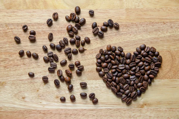 Granos de café en forma de corazón en panel de madera — Foto de Stock