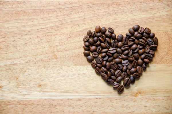 Grains de café en forme de coeur sur panneau en bois — Photo