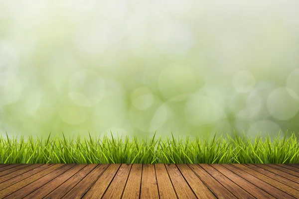 Suelo de madera, hierba y fondo borroso verde — Foto de Stock
