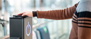 Erkek, akıllı telefonu kablosuz şarj cihazına ya da şarj aletine bağlıyor. Kamu alanındaki cep telefonu elektrik yükleme istasyonu.