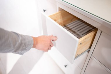 Erkek el çekme ve beyaz ahşap dolaptaki çekmeceyi açma. Ev eşyaları ve dekorasyon alışveriş konsepti