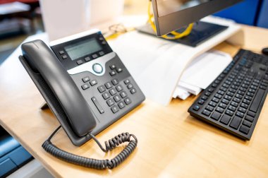 Çağrı merkezi ve müşteri hizmetleri yardım masası. Ofisteki çalışma masasında sabit telefon ve masaüstü bilgisayarı. İş iletişim desteği kavramı