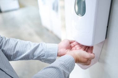 Ofiste temizlik yapmak için otomatik alkol makinesi kullanan erkek eller. Enfeksiyon önleme konsepti. Kamu binasında kaydet ve temizle.