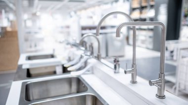 Erkek el mobilya dükkanında paslanmaz çelik musluğu seçiyor. Ev mutfağı için geliştirme.