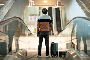 Seyahat sigortası konsepti. Seyahat makinesinde bavul ve dijital tablet taşıyan Asyalı turist ya da havaalanı terminalinde yürüyüş yolu.