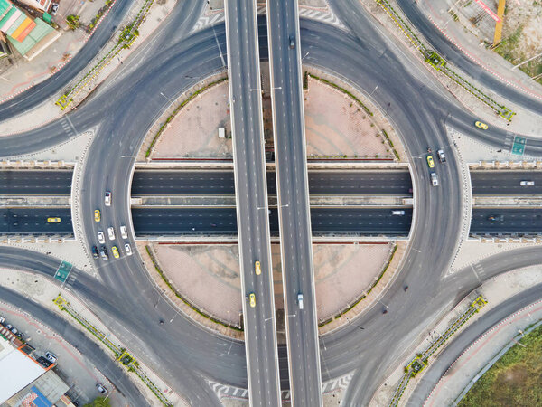 Aerial view of road intersection with roundabout. Urban highway interchange with cars speeding. Junction network of transportation taken by drone.