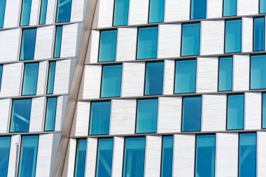 Beyaz duvarda mavi cam pencere desenli modern bina cephesi. Mimarlık ve inşaat konsepti