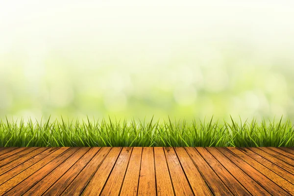 Hierba con fondo borroso verde y suelo de madera — Foto de Stock