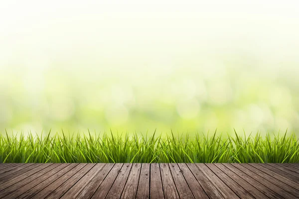 Hierba con fondo borroso verde y suelo de madera — Foto de Stock