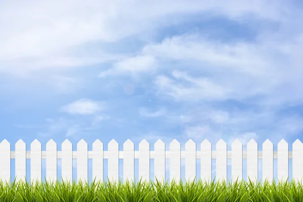 Gräs och staket under blå himmel och moln — Stockfoto