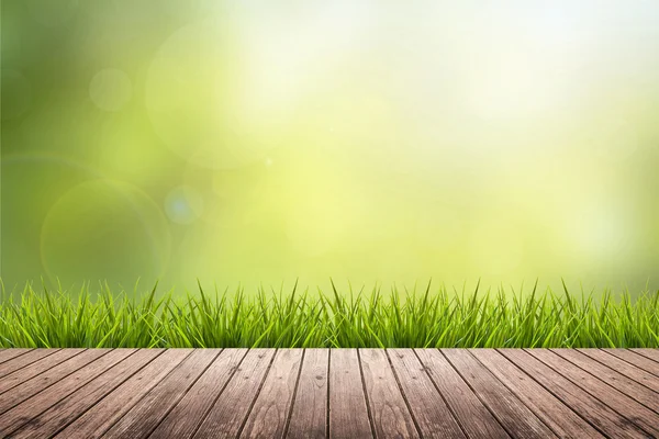 Gräs med gröna suddig bakgrund och trägolv — Stockfoto