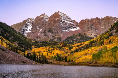 Şafakta kestane rengi çanlar. Elk dağlarındaki çan biçimli tepeler ve gölün üzerinde sarı kavak ağacı ormanı. Colorado, ABD 'de sonbahar yaprakları arasında ünlü sonbahar manzarası