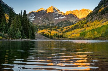 Güneş doğarken kestane rengi çanlar. Elk dağlarındaki çan biçimli tepeler ve gölün üzerinde sarı kavak ağacı ormanı. Colorado, ABD 'de sonbahar yaprakları arasında ünlü sonbahar manzarası