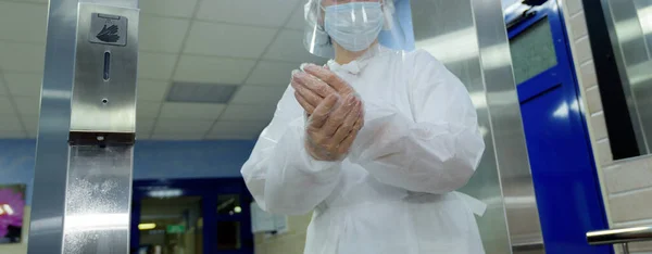 A doctor in a protective suit wipes his hands in the hospital.