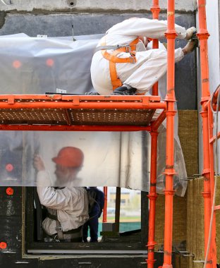 İnşaatçı inşaat alanında kask, gözlük ve koruyucu ekipman takarak bölgeyi ölçüyor..