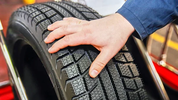 Tire production in the factory, tire blank. Ready tire, man\'s hand checks the tread.