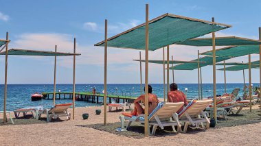 Türkiye 'de plaj, kumsalda güneşlenen turistler. Denizde iskele.