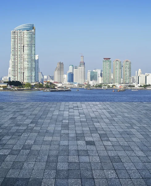 Een lege scène van een steen tegel vloer met stad toren achtergrond — Stockfoto