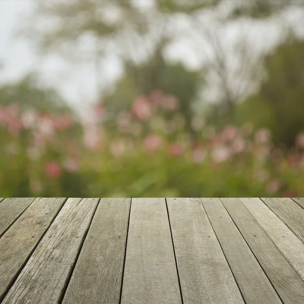 Suelo de madera viejo vacío con flor rosa borrosa y árbol, para su — Foto de Stock