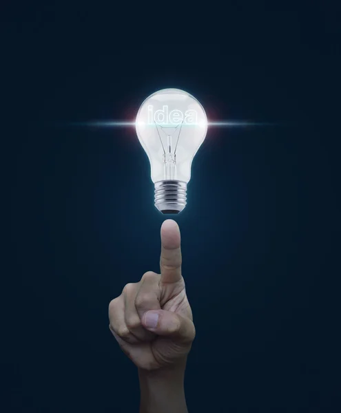 Hand pointing to light bulb with blue spot light and idea word o — Stock Photo, Image