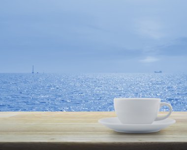 Masa üzerinde tekne siluet deniz ve mavi gökyüzü ile beyaz Kupası
