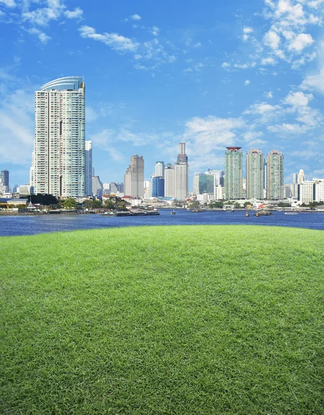 Empty scene of green grass field with city tower — Stock Photo, Image