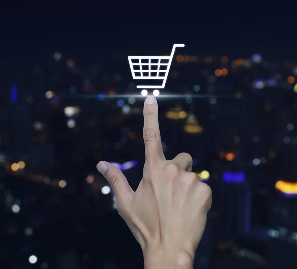 Hand te drukken shopping cart pictogram over wazig licht stad toren b — Stockfoto