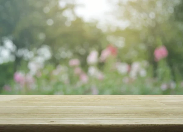 Mesa de madera vacía con flor rosa borrosa y árbol, tono suave — Foto de Stock