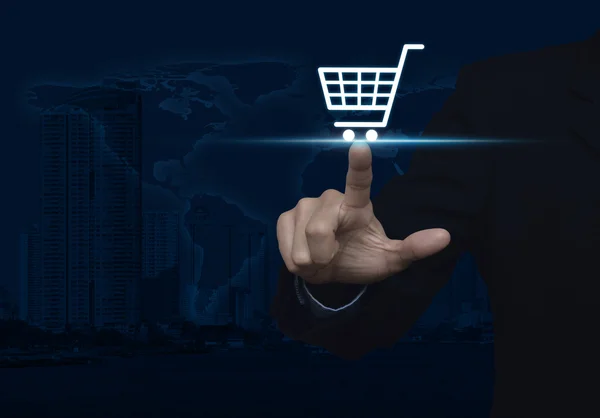 Businessman pressing shopping cart icon over map and city tower, — Stock Photo, Image