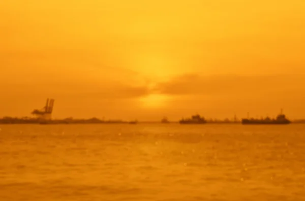 Размытие грузового судна с судоходным портом над закатом моря — стоковое фото