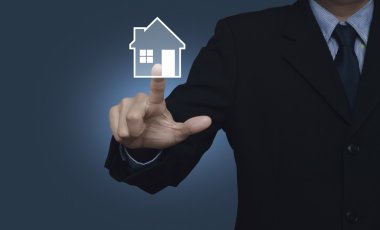 Mavi arka plan, emlak ev simgesini basarak işadamı 