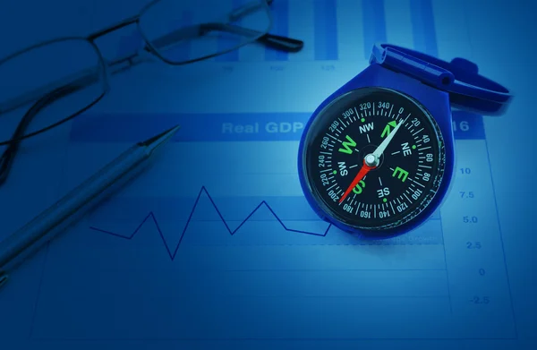 Blue compass with pen and glasses on growth financial chart and — Stock Photo, Image