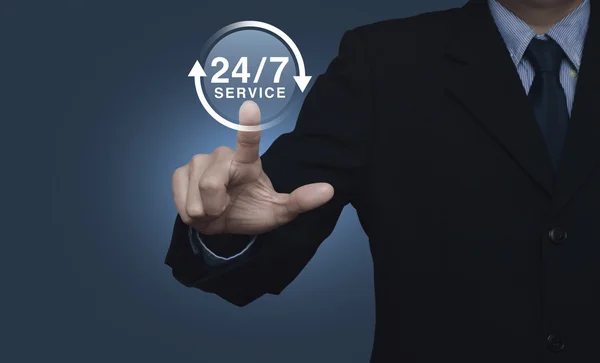 Businessman pressing button 24 hours service icon on blue backgr — Stock Photo, Image