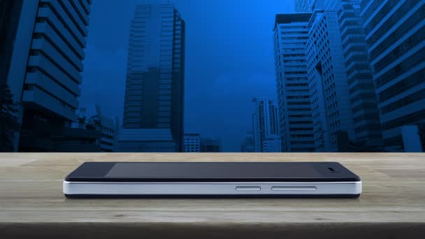 オフィスタワーや超高層ビルの上の木製テーブルの上の現代的なスマート携帯電話の画面上のショッピングカートフラットアイコン ビジネスショップオンラインコンセプト — ストック動画