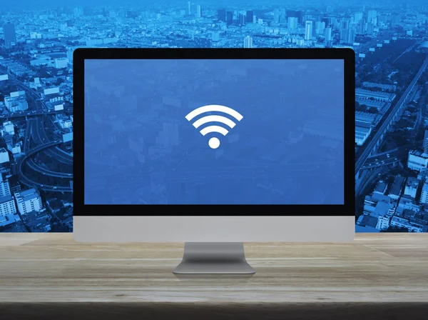 城市塔 高速公路和摩天大楼上木制桌子上的桌面现代计算机监控屏幕上的Wi Fi平面图标 — 图库照片