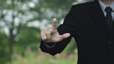 İş adamı parktaki bulanık çiçek ve ağacın üzerindeki simgeyle uçağa baskı yapıyor. İş seyahati sigortası ve güvenlik kavramı.