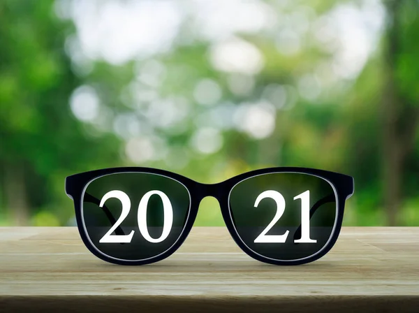 2021 White Text Black Eye Glasses Wooden Table Blur Green — Stock Photo, Image