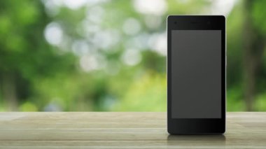 Modern akıllı cep telefonu ekranındaki mikrofon yassı simgesi parktaki bulanık yeşil ağacın üzerindeki ahşap masa üzerinde iş iletişimi online konsepti
