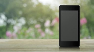 Hediye kutusu mutlu yeni yıl 2021 modern akıllı cep telefonu ekranında ahşap masanın üstünde pembe çiçek ve bahçede ağaç üzerinde düz simge mutlu yıllar 2021 mağazası online konsept