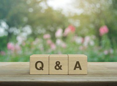 Q ve A kelime blok küpleri üzerinde ahşap masa üzerinde bulanık pembe çiçek ve bahçede ağaç üzerinde, sık sık sorular sordu iş müşteri hizmetleri ve destek kavramı