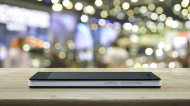 Modem akıllı cep telefonu ekranında, bulanık ışıkta ve alışveriş merkezinin gölgesinde, iş güvenliği ve güvenlik online konseptinin üzerinde, mozaik masaların üzerinde, CCTV kamera yassı simgesi
