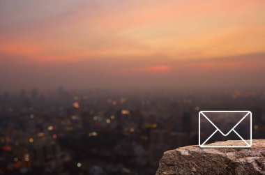 Sıcak gün batımında şehir manzarası bulanıklığı, iş dünyası müşteri hizmetleri ve çevrimiçi konsepti desteklemek üzerine Rock Dağı 'ndaki posta düzlüğü simgesi