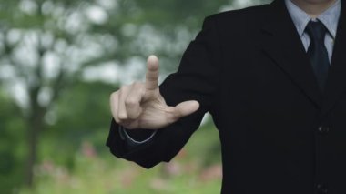 İş adamı parktaki bulanık çiçek ve ağaç üzerinde harita nokta konumlandırma düğmesine basıyor, harita işaretleyicisi çevrimiçi konsepti