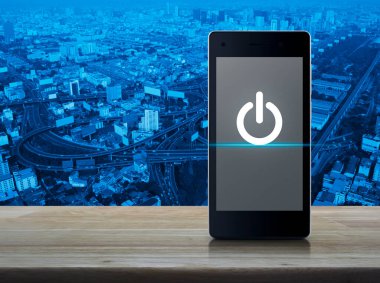 Elektrik düğmesi düz simgesi modern akıllı cep telefonu ekranı ahşap masa üzerinde şehir kulesi, sokak, ekspres yol ve gökdelen üzerinde, iş kurma online konsepti
