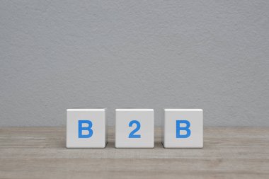 Beyaz blok küpleri üzerine B2B harfi beyaz duvar arkaplanı üzerinde ahşap masa, işletmeden iş pazarlama ve strateji çevrimiçi konsepti