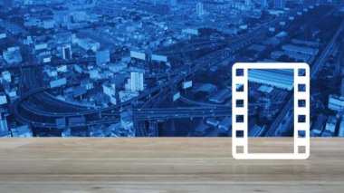 Modern şehir kulesinin, caddenin, otobanın ve gökdelenin, iş sinemasının çevrimiçi konseptinin havadan görünüşü üzerine tahta masanın üzerinde film yassı simgesiyle oyna