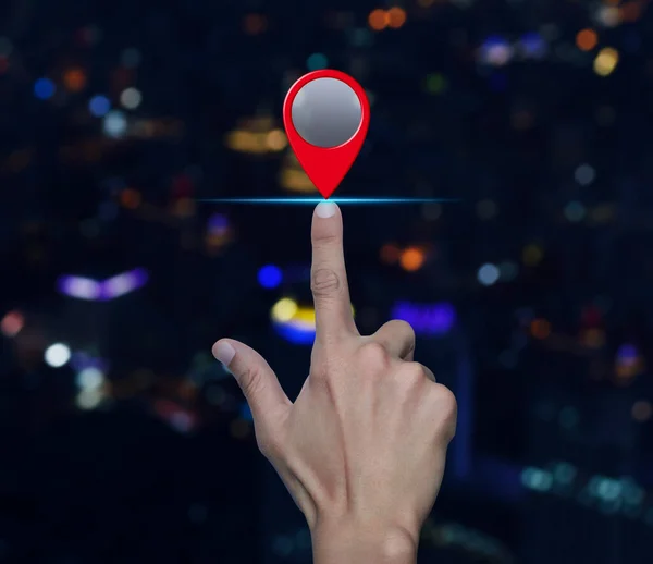 Hand pressing map pin point location button over blur colorful night light modern city tower and skyscraper, Map pointer navigation concept