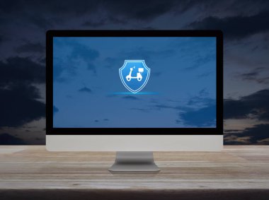 Günbatımı gökyüzü üzerinde ahşap masa üzerinde masaüstü modern bilgisayar monitörü üzerinde kalkan düz simgesi olan motosiklet, iş motosikleti sigortası çevrimiçi konsepti