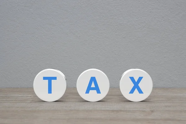 白墙背景上木制桌子上白色圆形的Tax字母 商业和金融概念 — 图库照片